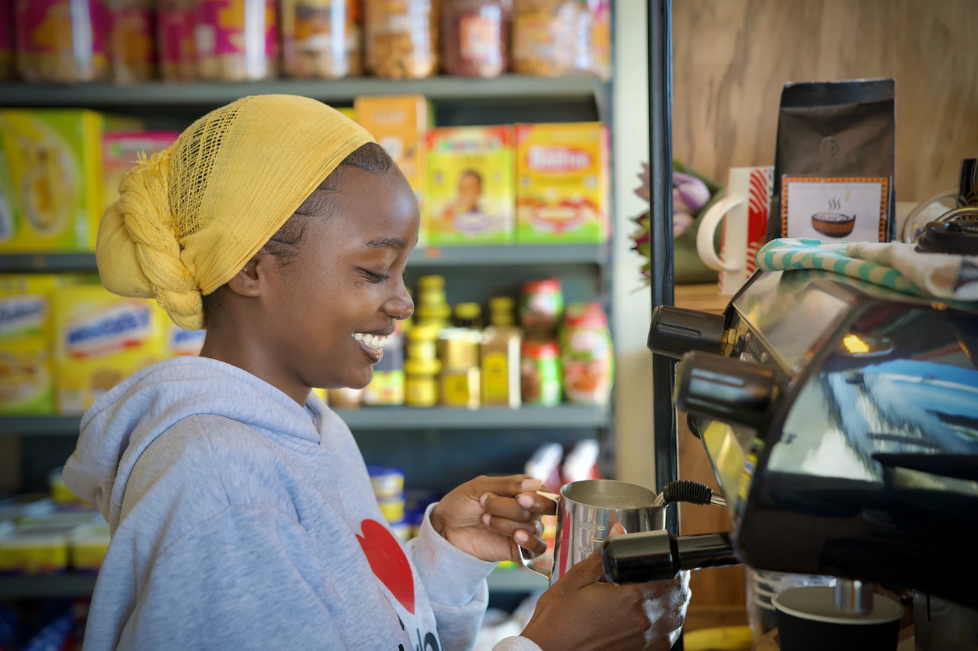 A smiling café owner making coffee behind her counter