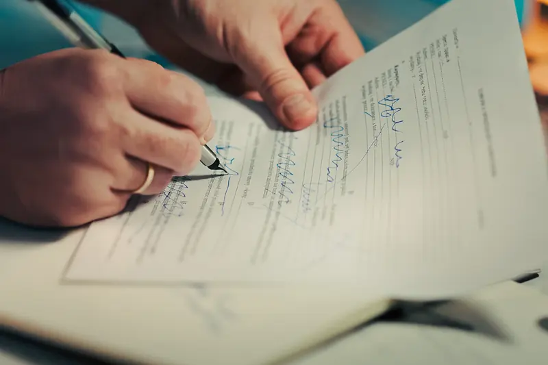 Close-up of a hand signing a document with a pen
