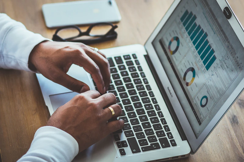Hands typing on a laptop that shows financial charts