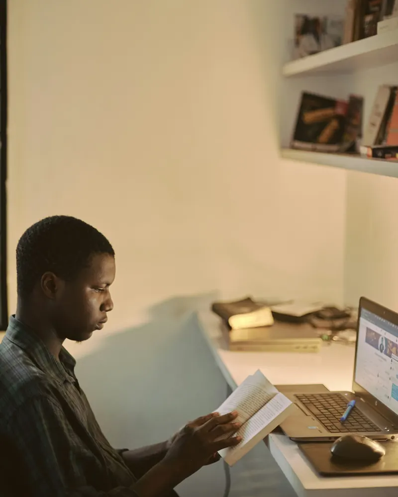A man reviewing printed records at his desk beside a laptop