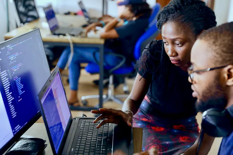 Two people working through a task together at their laptops